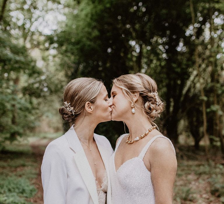 Two brides share a romantic kiss for their wedding couple portraits at woodland wedding 