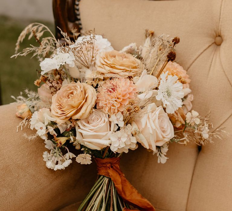 Neutral wedding bouquet tied with orange ribbon for boho style outdoor safari wedding with nature theme 