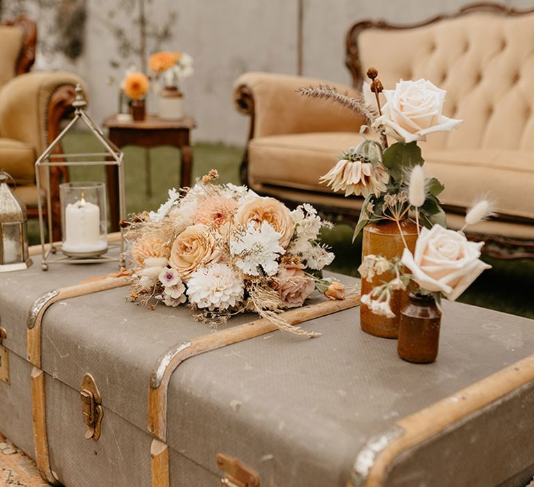 Relaxed outdoor wedding area decorated with neutral wedding flowers, candle lanterns and rustic wedding decor 