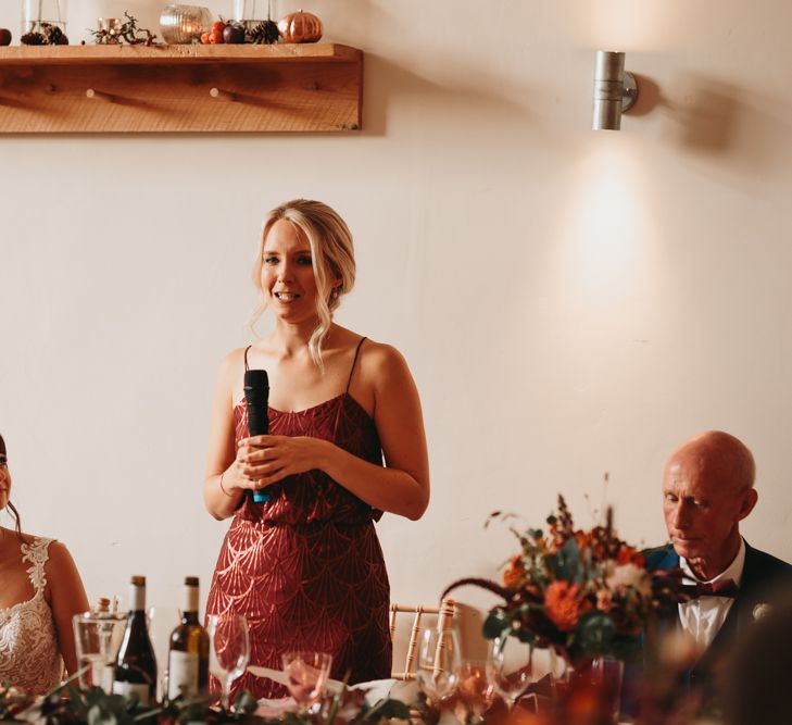 Bridesmaid in rust coloured dress delivering a speech