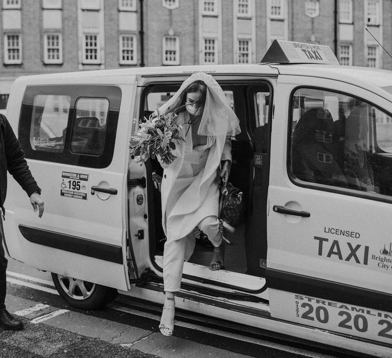 bride in jumpsuit getting out of a taxi 