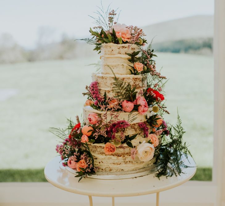 four tier semi-naked vegan wedding cake with flowers