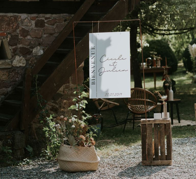 Hanging wedding sign flanked by wooden crates and wicker baskets