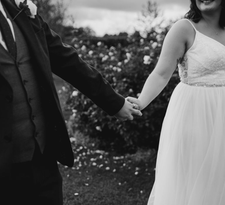 Bride and groom holding hands in flower garden