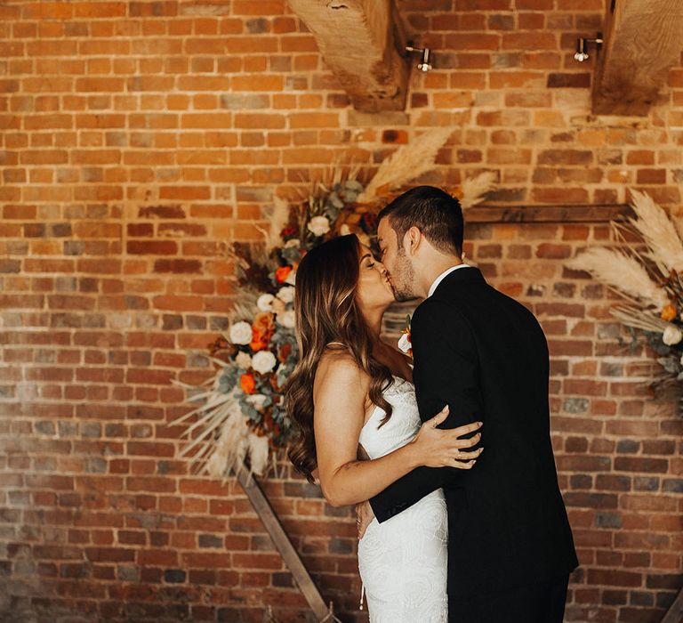 Bride and groom kiss in front of hexagonal wedding decor