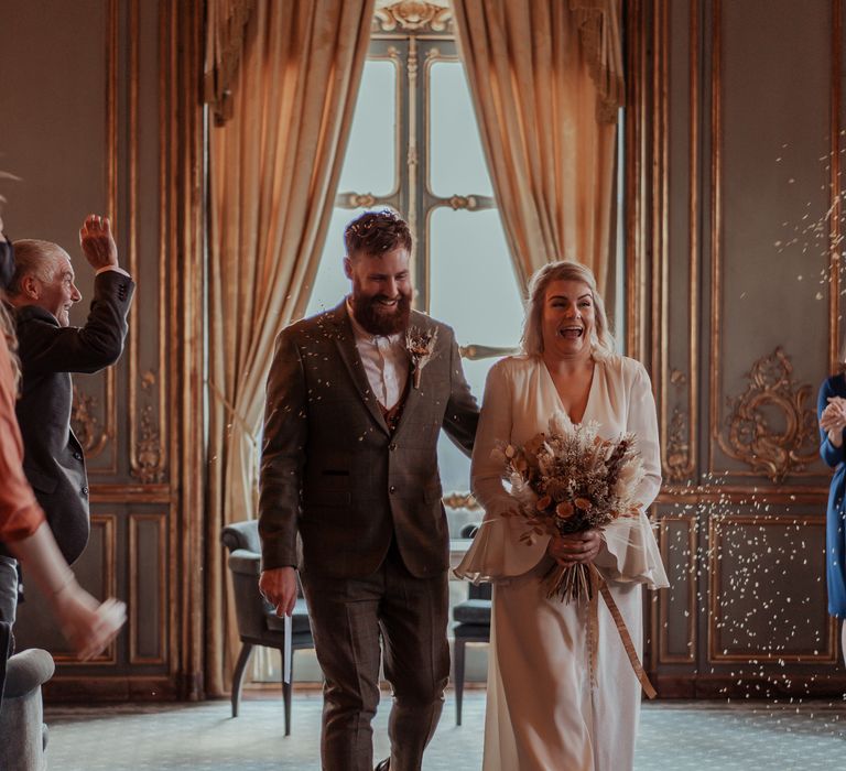 Bride & groom walk through confetti laughing