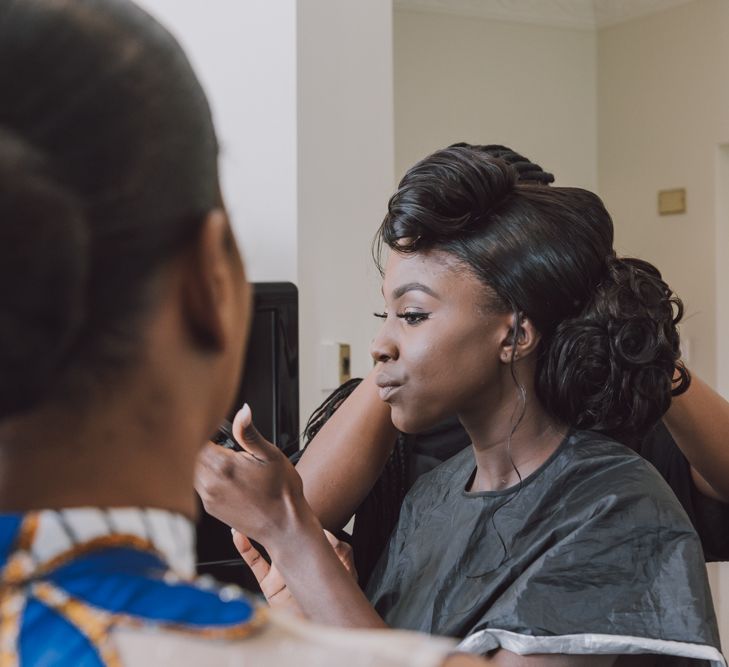 A Black bride is getting her hair and makeup done ready for her wedding