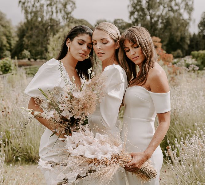 Bridesmaid portrait in an off the shoulder midi dress, and jumpsuits holding dried and fresh flower neutral bouquets 