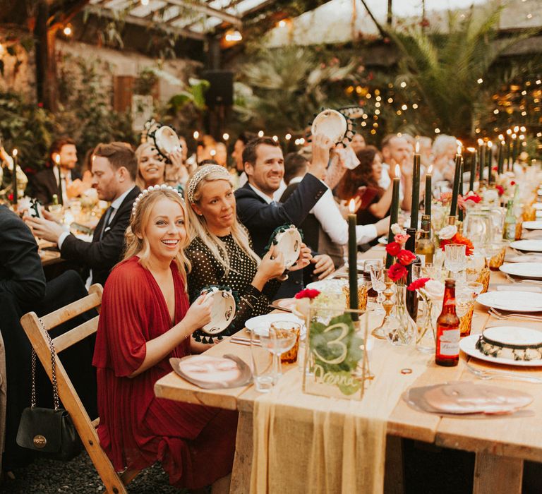 Anran glasshouse wedding reception with wedding guests sitting at wooden tables and chairs provided by Virginias Vintage Hire 