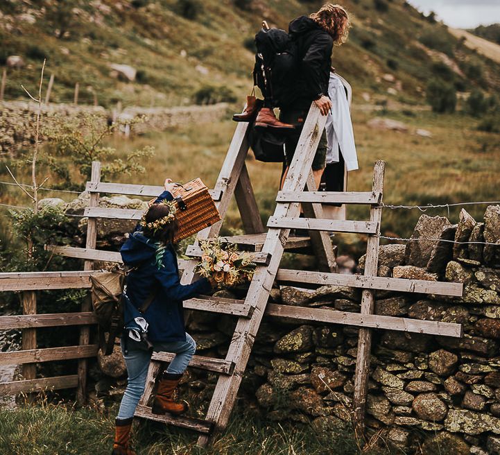 Bride & groom carry wicker baskets in the Lake District countryside