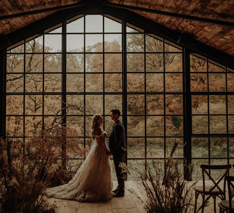 Wedding ceremony with dried flower arrangements in front of the Crittall windows at Hidden River Cabins wedding venue 