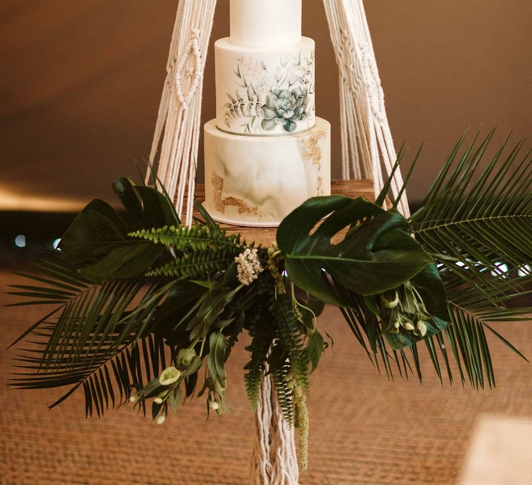 Wedding cake suspended with macrame and green foliage decor