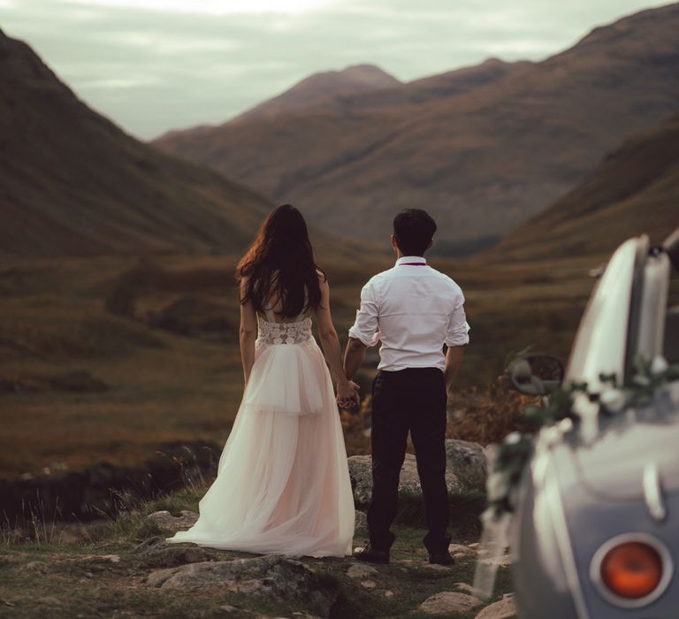 Couple stand by vintage car in Scotland during rock climbing engagement session