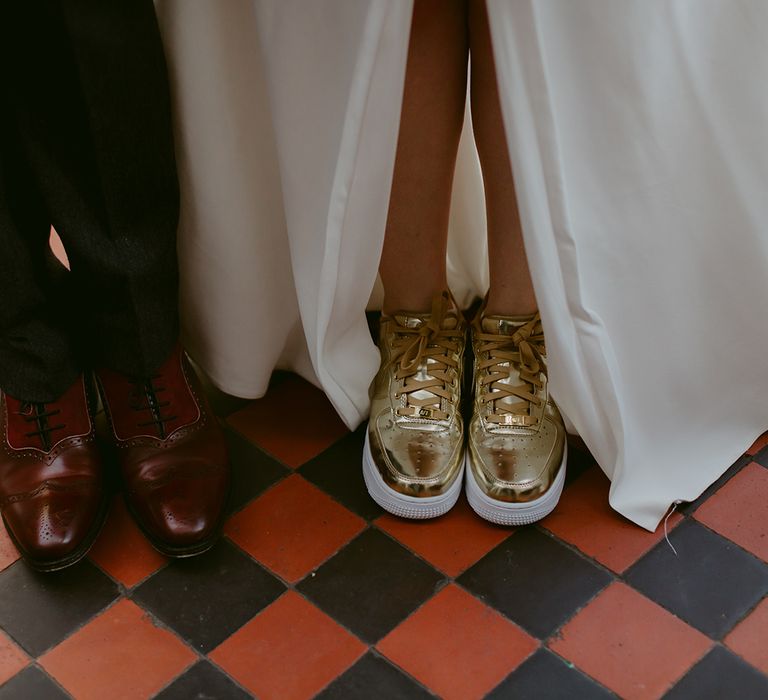 Grooms feet in burgundy brogues and brides feet in gold Nike Air Force 1 trainers