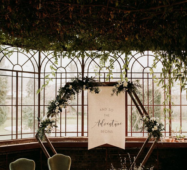 Glasshouse wedding ceremony with hexagon altar, fabric sign and velvet chairs 