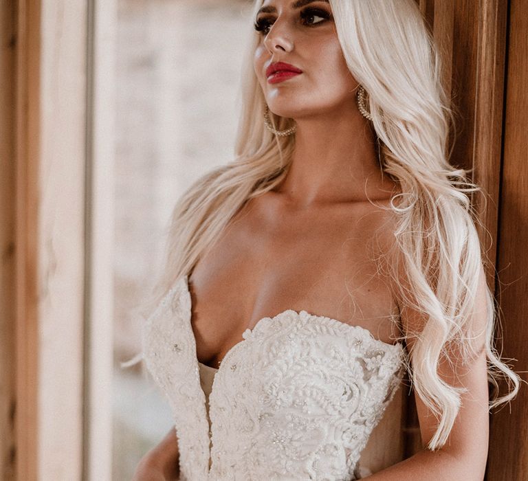 Stylish bride with blonde hair, smokey eye makeup and red lipstick wearing a sweetheart neckline wedding dress