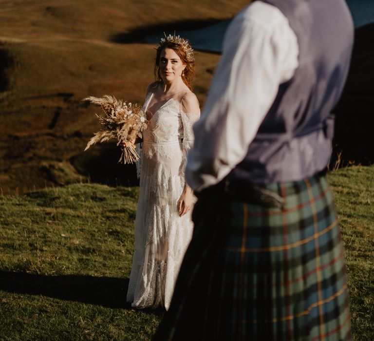 Groom looks over to bride on the hillside 