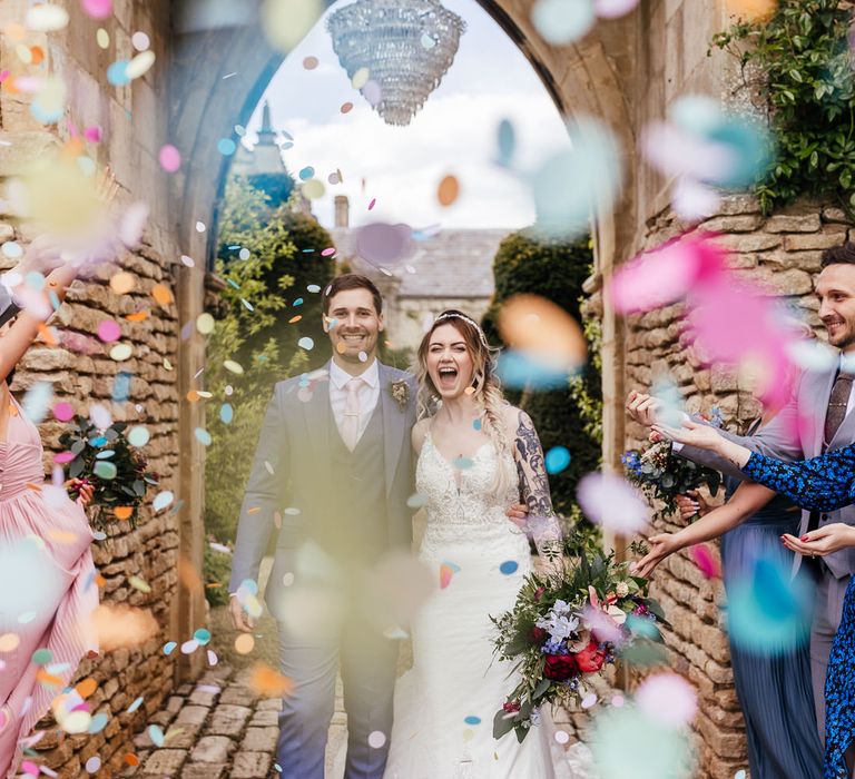 Bride & groom walk through wedding party throwing colourful confetti on their wedding day