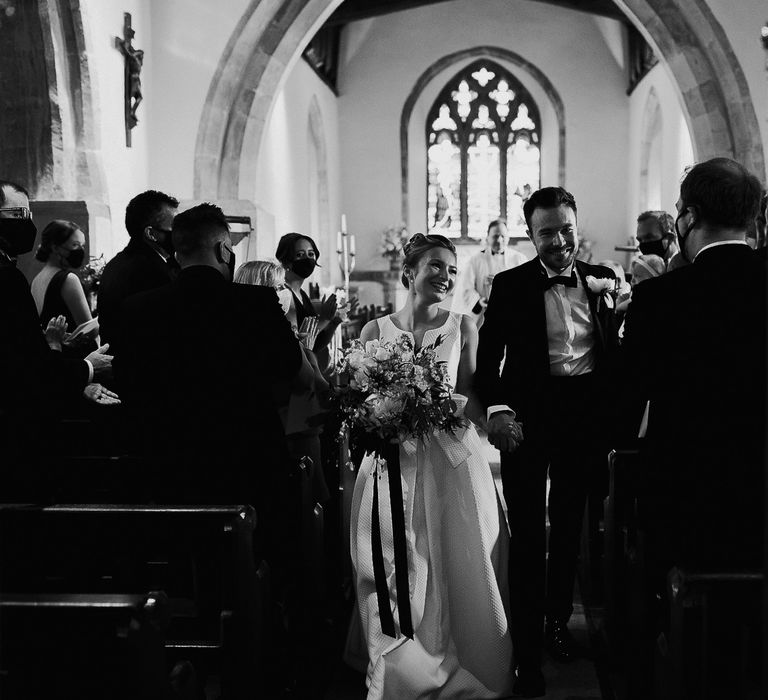 Bride & groom hold hands as they leave wedding ceremony on their wedding day