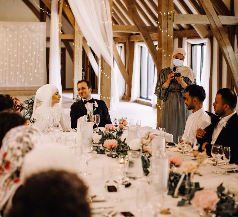 Wedding party at rustic barn wedding venue with fairy lights and white drapery