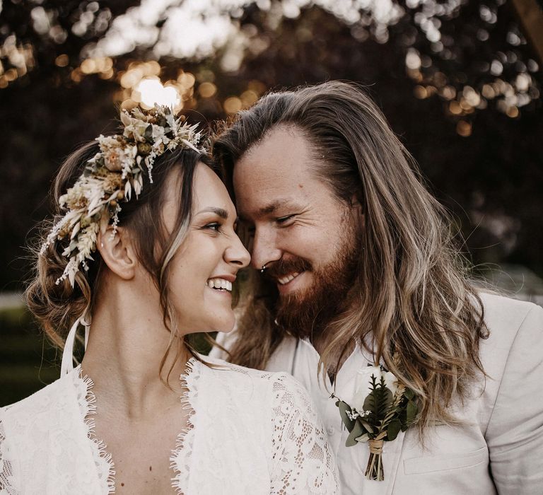 Intimate bride and groom portrait with groom in a beige suit and the bride in a lace wedding dress with plunging neckline 