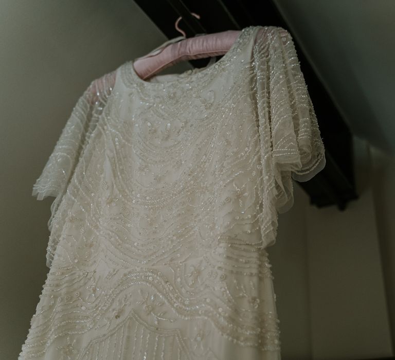 Wedding gown with batwing sleeves and sequinned embellishment hangs on the morning of wedding day