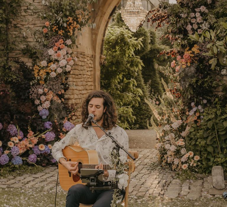 Musician singing and playing guitar in front of the castle arch at Euridge Manor 