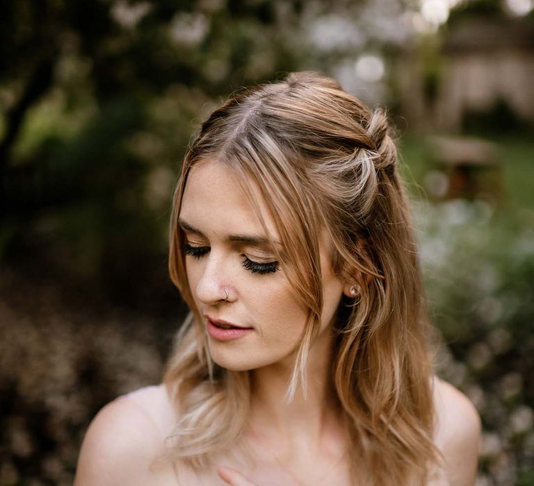 Bride in a blush pink wedding dress with a half up half down wedding hairstyle 