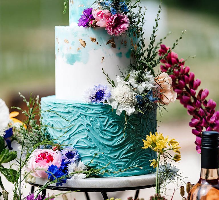 Marble and metal cake stand with turquoise buttercream wedding cake decorated with wildflowers 