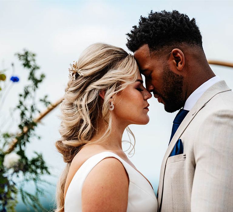 Intimate bride and groom portrait with groom in a beige suit and bride in a princess wedding dress with straps 