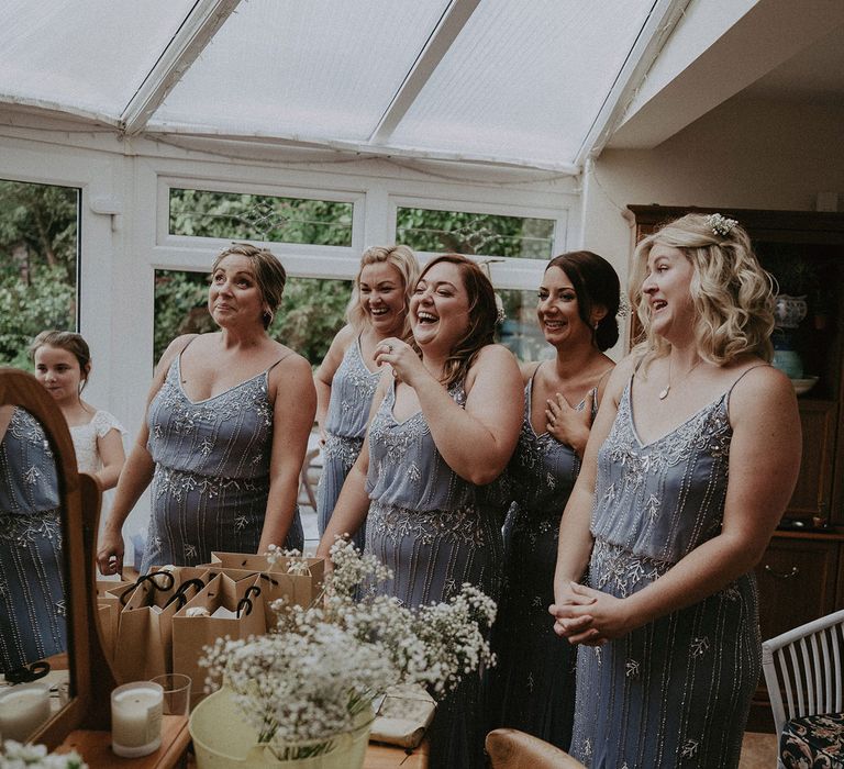 Bridesmaids in blue beaded cami bridesmaids dresses standing in conservatory before Isle of Wight wedding with macrame wedding decor