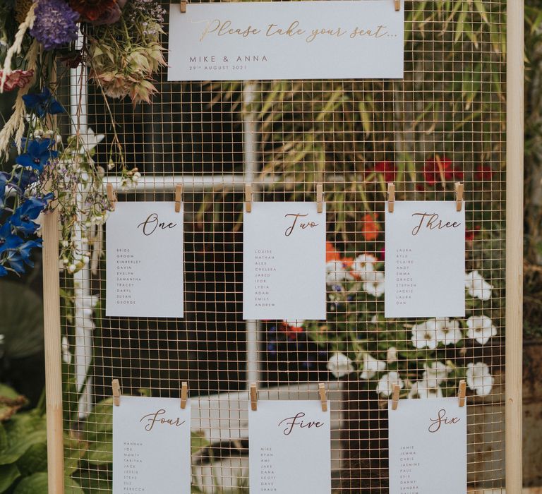 Take a seat table plan at wedding with pastel floral decor