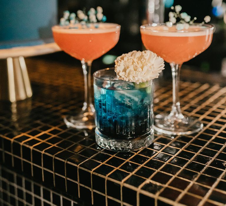 Pink and blue cocktails on the bar at a stylish teal wedding reception 