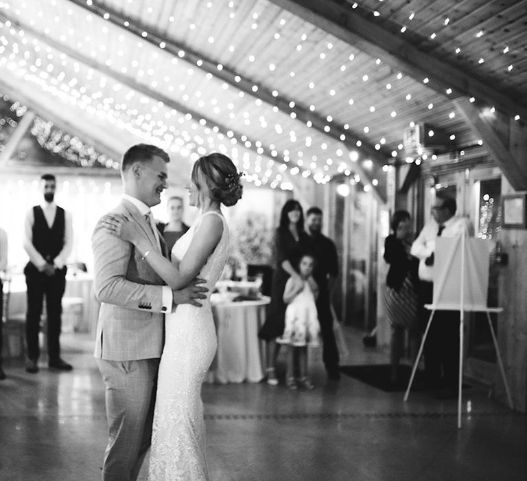 Bride and groom dance under fairy lights