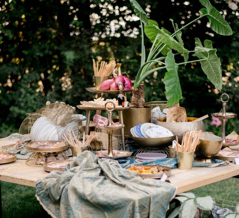 Wooden table filled with food and dusty blue tablecloths with patterns