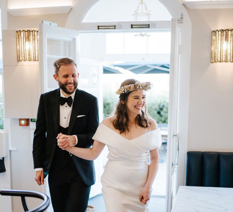 Bride & groom walk hand in hand into wedding reception