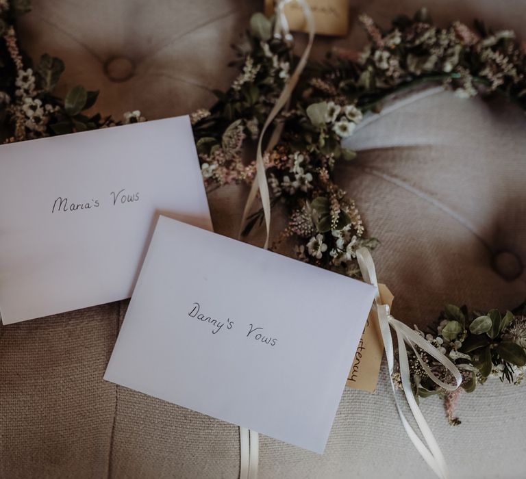 Dried flower crowns with name tags and bride and groom's vows in white envelopes for Cotswolds wedding