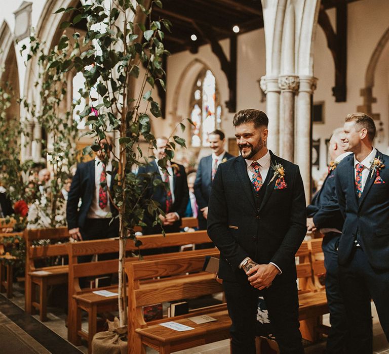 Groom and best man at the church altar in a navy suit and floral Liberty print tie