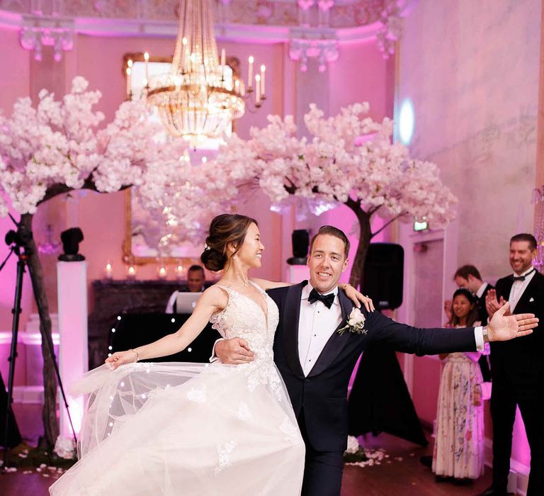 Groom lifts his bride and spins her during first dance at wedding ceremony