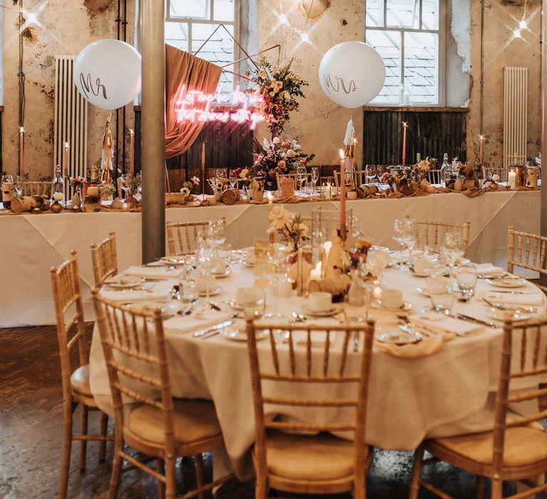 Wedding reception room at Holmes Mill with white round wedding tables, wooden chairs and elegant wedding styling with candles and fairy lights