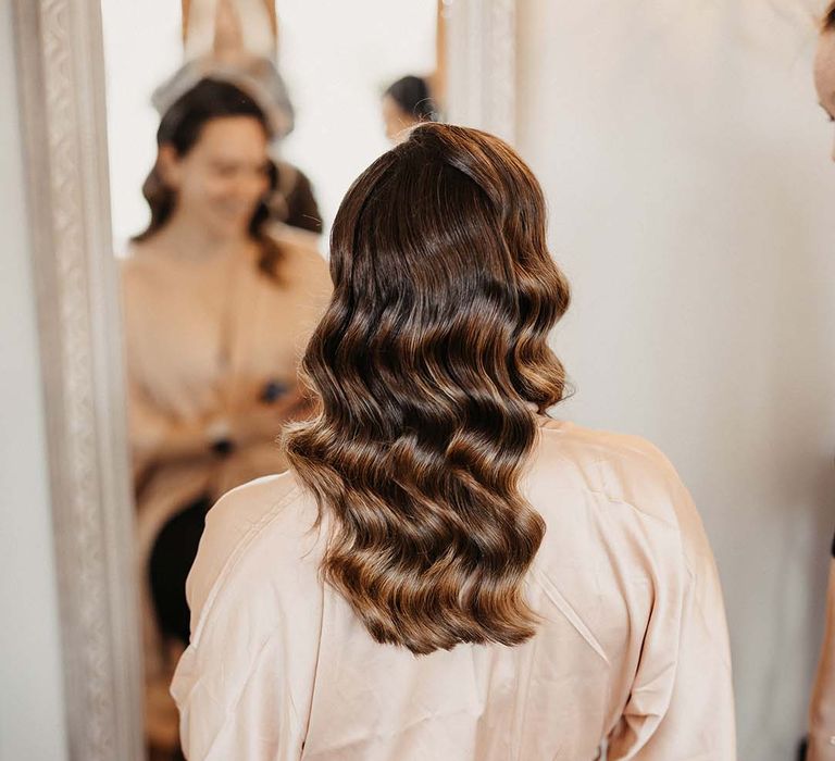 Bridesmaid in pale pink satin dressing gown with Hollywood style curled hair