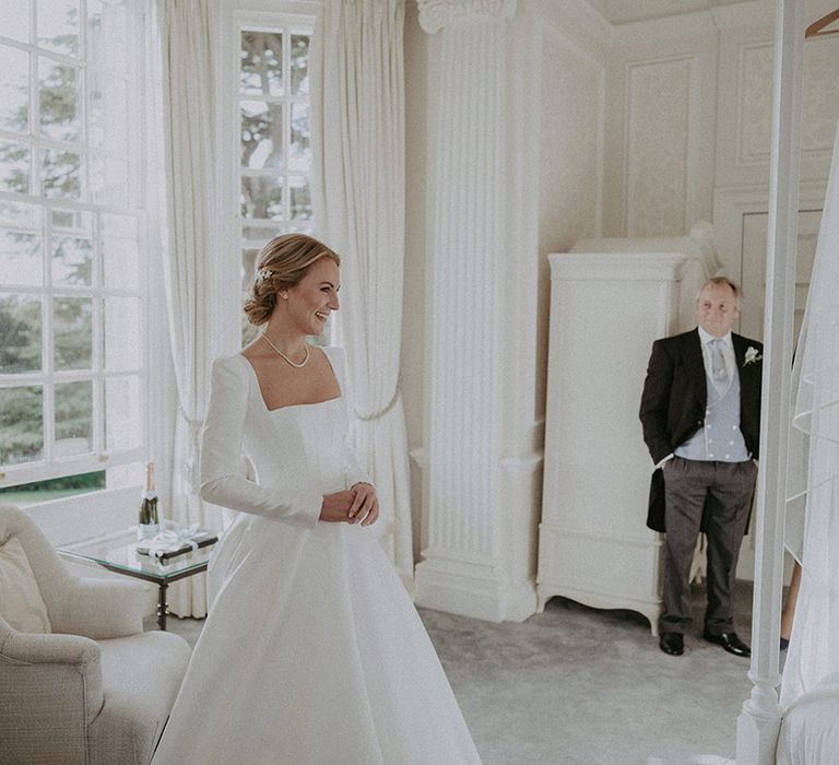 Bride in long white wedding dress with square neck, full skirt and pearl necklace 