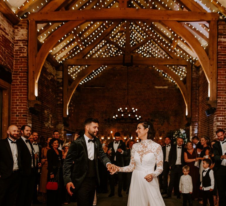 Bride and groom begin their first dance together at cosy and rustic wedding barn venue