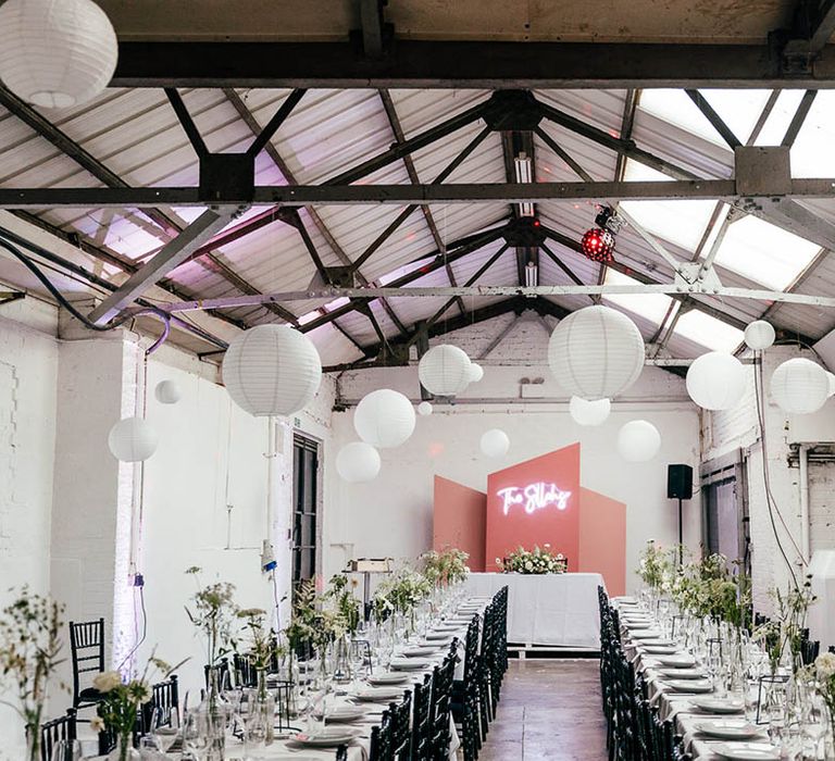 Industrial wedding venue with hanging white paper lanterns, neon sign and pink details 