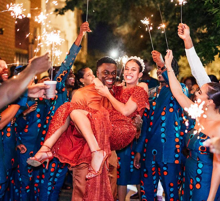 Bride and groom change into traditional orange Sierra Leonean outfits with bride wearing a pearl headband