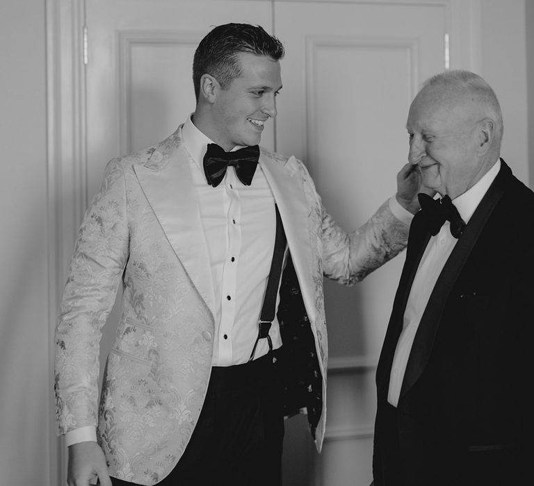 Groom smiles with grandfather in black tie on his wedding day