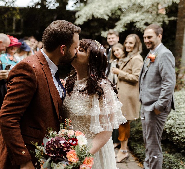 Bride and groom share a kiss after their confetti exit from intimate micro wedding