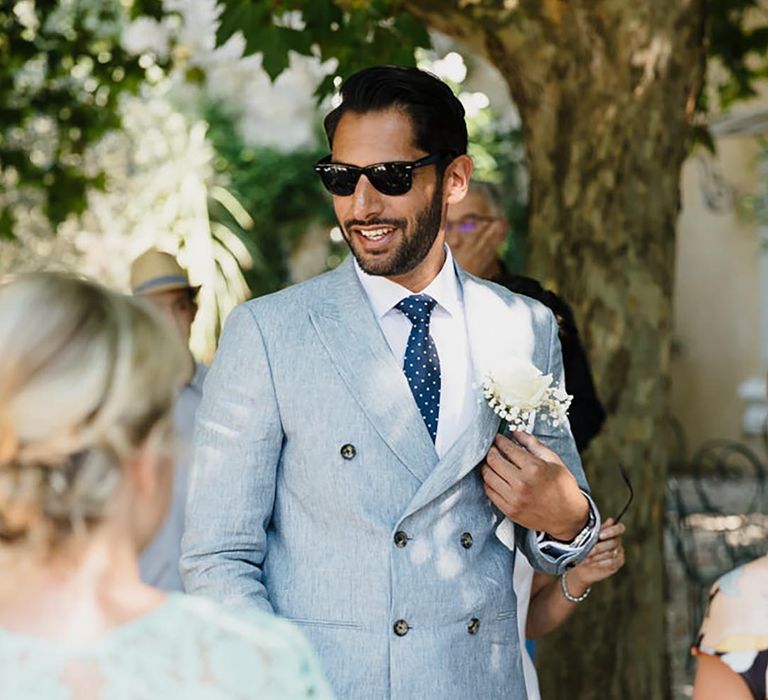 Groom in a light blue double breasted suit wearing sunglasses at his destination wedding 