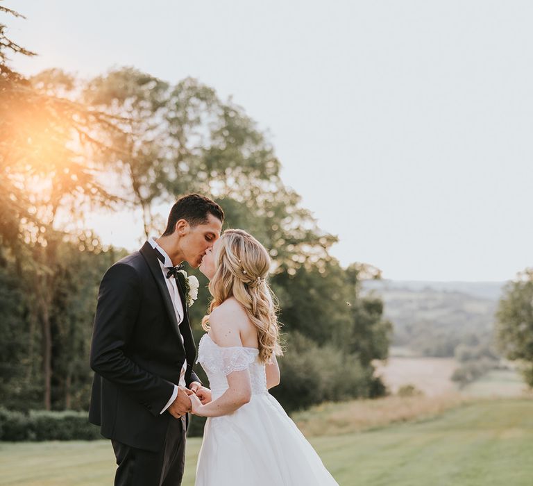 Bride and groom kiss overlooking the countryside around Hedsor House