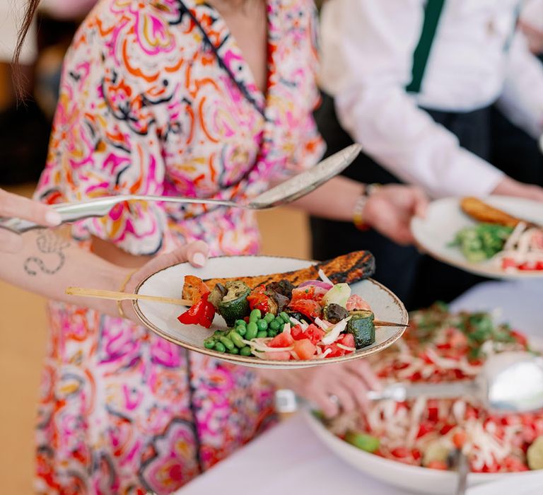 Guests place colourful vegan salads on their plates for BBQ during sustainable wedding 